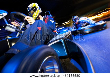 Two go-cart drivers battling in a competitive race on an indoor circuit Royalty-Free Stock Photo #64166680