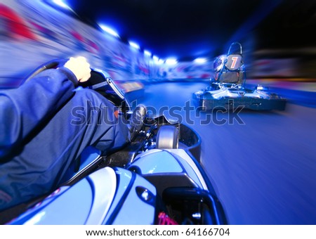 Two go-carts racing close to each other on an indoor race track Royalty-Free Stock Photo #64166704