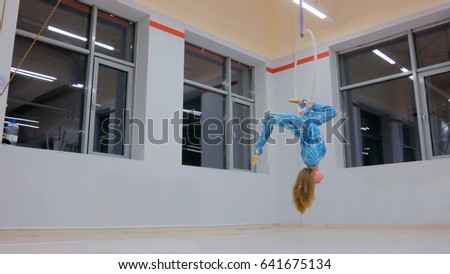 Plastic beautiful girl gymnast on acrobatic circus ring in blue suit. Aerial ring. Acrobatic and sport concept