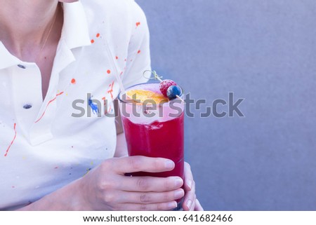 Girl in a white T-shirt and jeans holding raspberry cocktail. Summer drink concept. Copy space. Lifestyle, street food