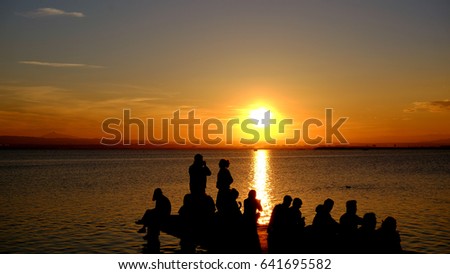 Sea landscape with orange sky and people figures watching it