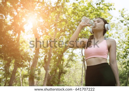 young beautiful asian fitness athlete woman drinking water after work out exercising at summer green park. Concept of healthy lifestyle