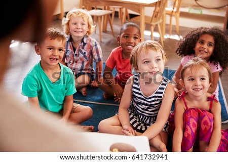 Teacher At Montessori School Reading To Children At Story Time Royalty-Free Stock Photo #641732941