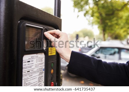 Close Up Of Man Putting Money In Parking Meter For Ticket Royalty-Free Stock Photo #641735437
