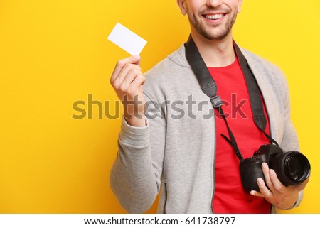 Male photographer with business card on color background
