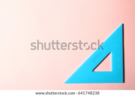 Blue plastic triangle on a pink background