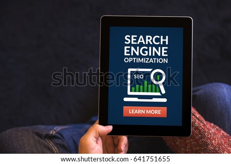 Hands holding digital tablet computer with search engine optimization (SEO) concept on screen. All screen content is designed by me. Flat lay