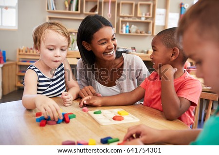 Teacher And Pupils Using Wooden Shapes In Montessori School Royalty-Free Stock Photo #641754301