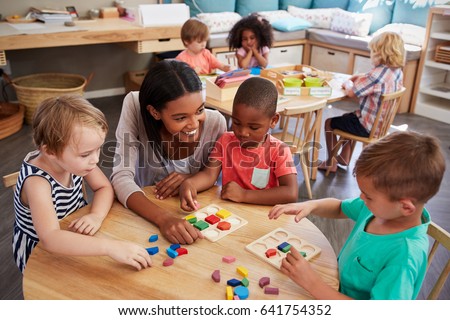 Teacher And Pupils Using Wooden Shapes In Montessori School Royalty-Free Stock Photo #641754352