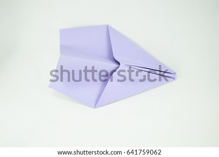 Violet paper plane on a white background, isolated. Concept (idea) of airlines, freedom, leadership, success,  and creativity. Close-up