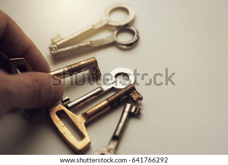 Man taking an old key, keys on the table