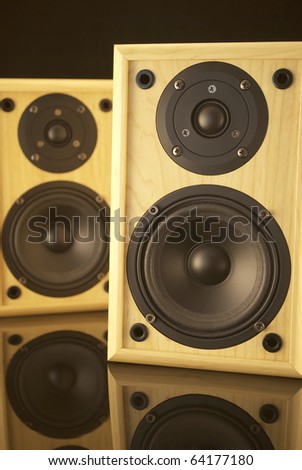 Royalty free stock image of a pair of speakers with a warm glow, against black and on a black reflective surface