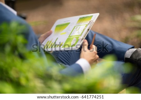 Young men analyze the chart results.discussing and using digital tablet to outdoor in the garden park.