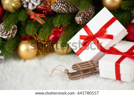 christmas decoration on fir tree branch closeup, wooden sledge toy, gifts, xmas ball, cone and other object on white blank space fur, holiday concept, place for text