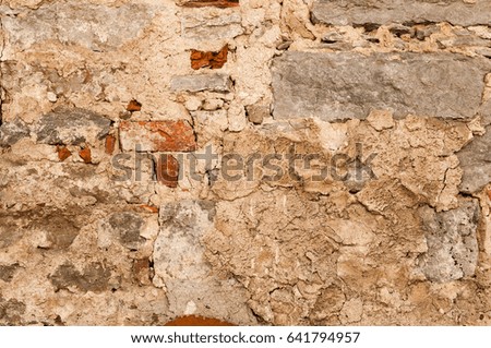 Old and damaged beige stone wall background texture close up. Aged bricks and cement. 