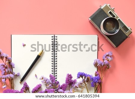Top view of blank space notebook paper and vintage camera on pastel pink color background  with flower 