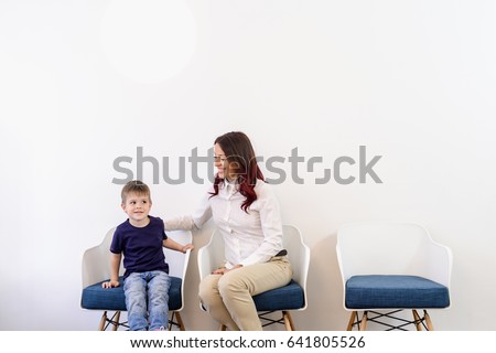 A boy child in doctors waiting room - reception with his mom. Kids first visit for a regular dentist exam 