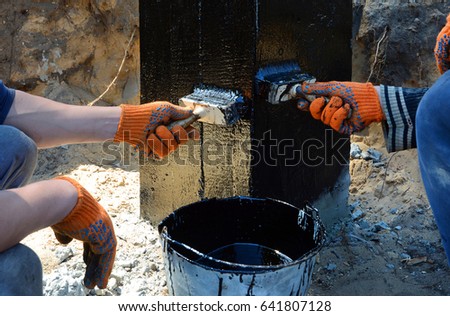 Contractor painting black coal tar or bitumen at concrete surface by the brush, a foundation Waterproofing for anti damp proofing. Royalty-Free Stock Photo #641807128