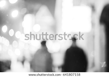 Silhouettes of two friends walking in the night city. High contrast black and white photo.
