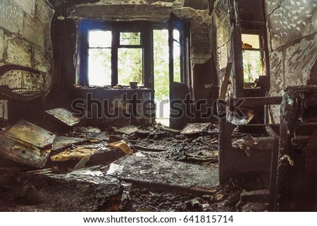 Burned room in burned abandoned house with light from balcony and window, Charred furniture and interior items, all in black soot