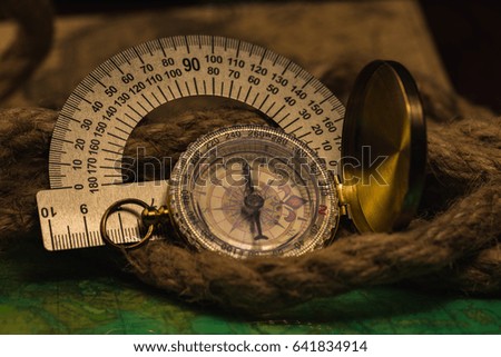 The compass and protractor lies on an old card