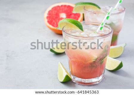 Cold pink cocktail with fresh grapefruit, lime and ice cubes on concrete background, paloma, copy space Royalty-Free Stock Photo #641845363