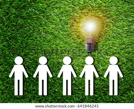 Think different concept, group of white paper people and light bulb on green grass background