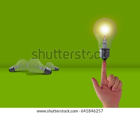 Think different concept, hand and light bulb on green background