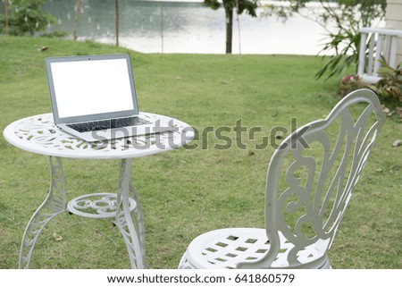 Laptop computer on white table in park.  freelance or remote work concept