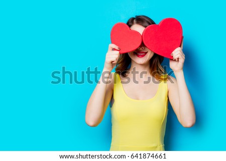 portrait of beautiful young woman with heart shaped gifts on the wonderful blue studio background