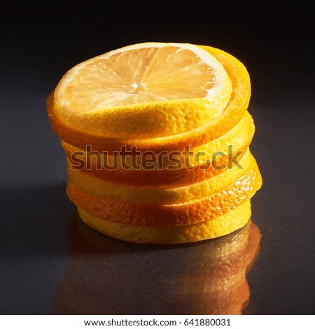 a stack of fresh orange and lemon isolated on a black background.