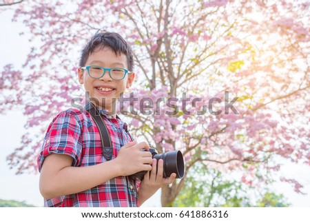 Young asian boy taking photo in park