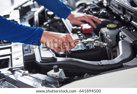 Hands of car mechanic with wrench in garage. Royalty-Free Stock Photo #641894500