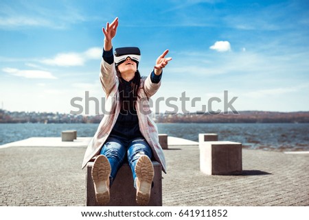 Brunette girl in virtual reality glasses have fun in the park