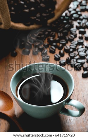 Hot Coffee cup with sack inside by coffee bean on the wooden table