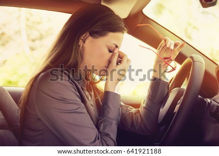 Business woman having headache taking off her glasses has to make a stop after driving car in traffic jam on rush hour. Exhausted, overworked driver concept. Royalty-Free Stock Photo #641921188