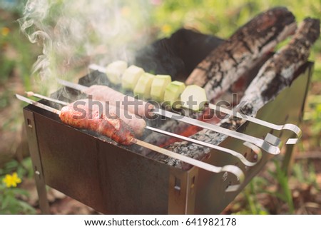 Grilled vegetables and sausages on braizer, summer barbecue in the forest