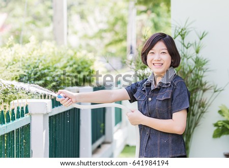 Asian women standing Spraying a tree in garden at her house