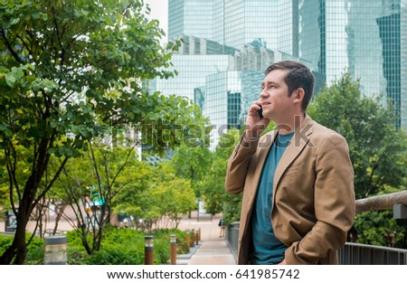 Businessman. Happiness businessman with phone around skyscrapers in La Defence district in Paris City with sky background.