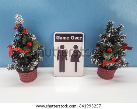 The white Game over sign is between a small Christmas tree.
