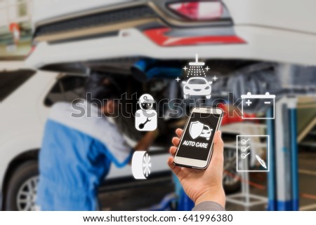 auto care application on smartphone with Blurred picture of car garage with cars being under maintenance and technicians for background