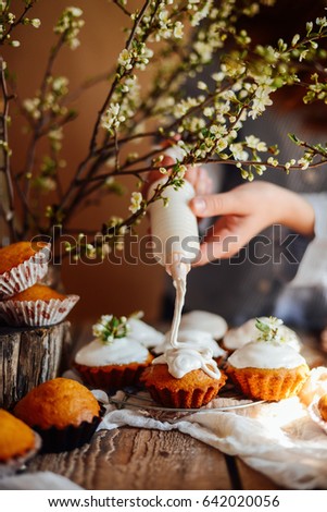 Female baker decorating tasty cupcake on the table. Cropped image of girl decorating cupcakes