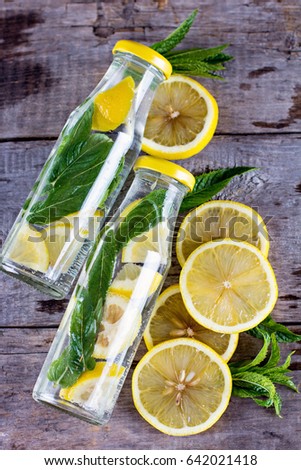 Water bottle with lemon and mint on a wooden table. Infused water with lemon, cucumber and mint on wooden background. Mineral water.summer drink.