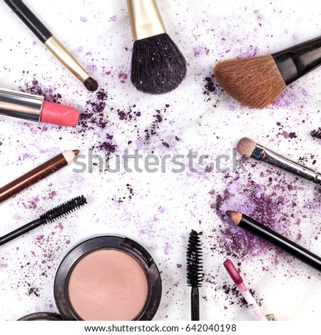 Makeup brushes, pencil, lipstick and other objects, forming a frame on a light background, with crushed powder and copy space. A square template for a makeup artist's business card or flyer design