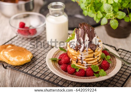 American pancakes with icecream and chocolate, herbs and berries around