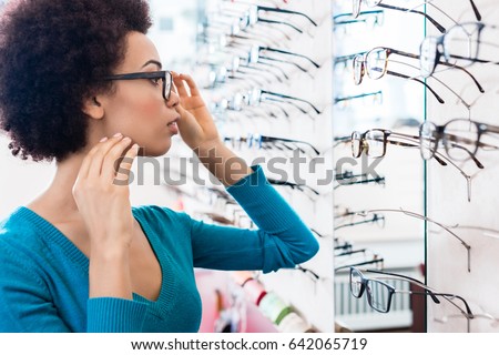 Black woman trying on glasses she wants to buy in optician store Royalty-Free Stock Photo #642065719