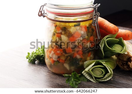 Jar with variety of pickled vegetables. Carrots, field garlic, parsley in glas. Preserved food