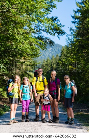 Family with four kids hiking in the mountains standing on path