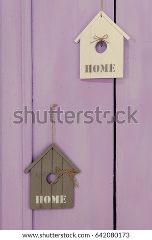 House interior decoration using little wooden houses with written word HOME on lavander background.