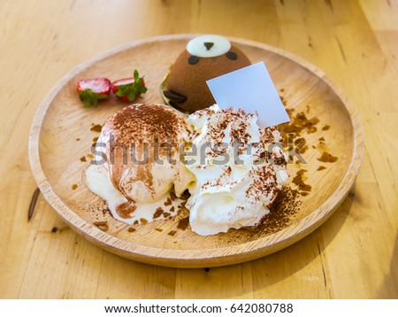 bear cake with ice cream and wipe cream have chocolate on top in wood dish 